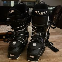 two black ski boots sitting on top of a wooden table