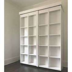 an empty white bookcase in the corner of a room