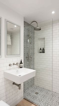 a bathroom with a sink, mirror and shower stall in white tile on the wall