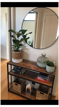 a mirror sitting on top of a wooden shelf next to a potted plant and books