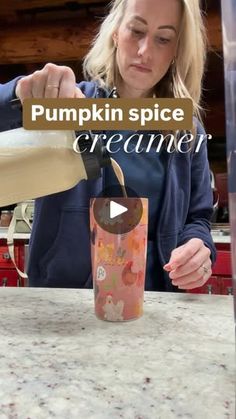 a woman pouring pumpkin spice into a cup