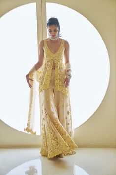 a woman in a yellow dress is standing near a round window