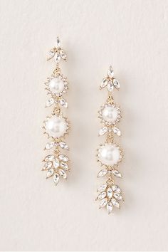 two pairs of earrings with pearls and crystals on the sides, one is gold and the other is white