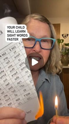 a woman holding a piece of paper with words on it and a lit candle in front of her