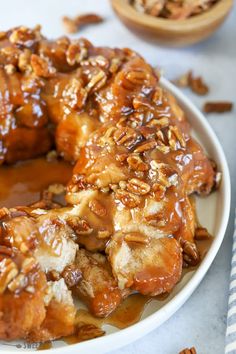 a bundt cake covered in caramel sauce and pecans on a white plate