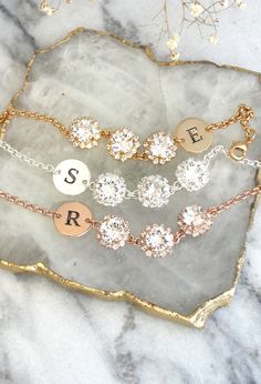 three personalized bracelets sitting on top of a marble slab with gold and silver charms