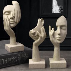 three white sculptures sitting on top of a table next to a book