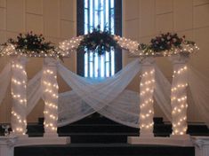 an altar decorated with flowers and lights in front of a church window at christmas time