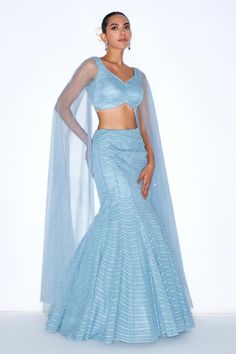 Blue mermaid style lehenga embellished with sequin scallop patterns. Comes with padded blouse with cape sleeves. 
Components: 2
Pattern: Embroidered
Type Of Work: Sequin
Neckline: V-neck
Sleeve Type: Cape sleeves
Fabric: Organza, net, Lining: Satin
Color: Blue
Other Details: 
Attached lining
Model Height: 6ft wearing size XS
Length: Lehenga: 45 inches
Closure: Lehenga and Blouse: Side zip
Occasion: Sangeet,Cocktail - Aza Fashions Glamorous Festive Mermaid Dress, Fitted Gown With Zari Work And Cape Sleeves, Blue Lehenga With Cape Sleeves And Dupatta, Sequined Sharara With Cape Sleeves For Receptions, Party Wear Choli With Sequins And Cape Sleeves, Fitted Gown With Sheer Dupatta And Cape Sleeves, Blue Party Sets With Cape Sleeves, Fitted Lehenga With Cape Sleeves For Evening, Evening Lehenga With Cape Sleeves Fitted