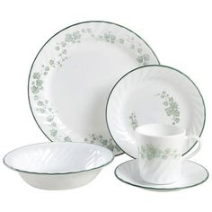 a white and green dinnerware set with flowers on the rim, cup and saucer