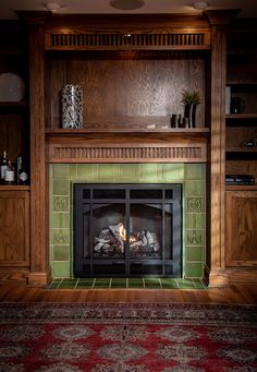 a fireplace in a living room with green tile and wood paneling on the walls