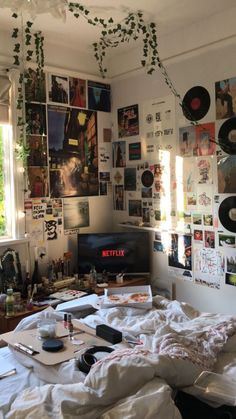 a messy bedroom with records on the wall and pictures all over the walls above it