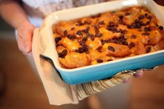 a person holding a casserole dish with raisins and cheese on it