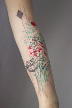 a woman's arm with tattoos and flowers on it