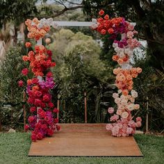 an outdoor ceremony setup with flowers on the aisle and greenery in the back ground