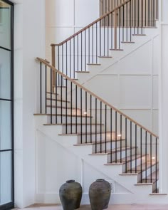 two vases sitting on the floor in front of a stair case next to a set of stairs