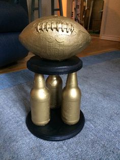 a gold football sitting on top of two beer bottles in front of a blue rug