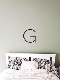 a white bed with black and white pillows on top of it next to a green wall