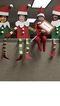 three elfs are hanging on the wall in an office