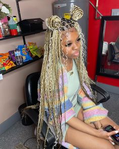 a woman sitting in a chair with long blonde hair and braids on her head