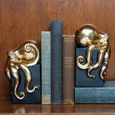 two golden octopus bookends sitting on top of bookshelves next to each other