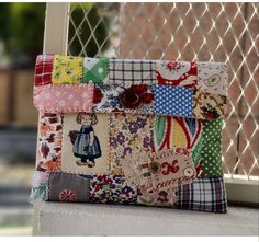 a colorful patchwork purse sitting on top of a window sill next to a fence