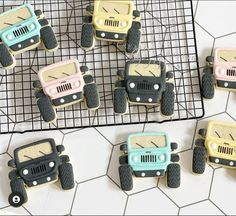 decorated cookies in the shape of jeeps on a cooling rack, with one cookie shaped like a car