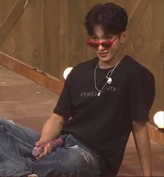 a young man sitting on the ground wearing sunglasses