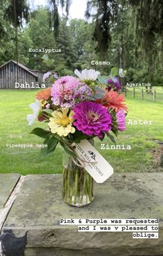 a vase filled with flowers sitting on top of a wooden table next to a field