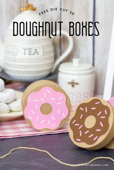 doughnut boxes with pink frosting and sprinkles sitting on a table