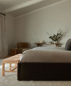 a bedroom with a bed, two chairs and a coffee table