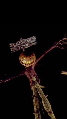 a scarecrow holding a sign that says halloween town