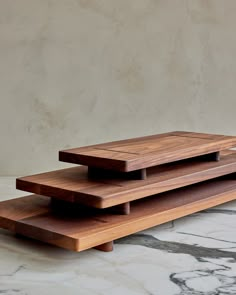 three wooden trays stacked on top of each other in front of a marble wall