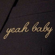 the words yeah baby are embroidered on a black suit