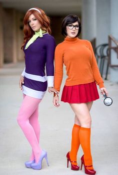 two women dressed in colorful clothing and high heels holding hands while standing next to each other