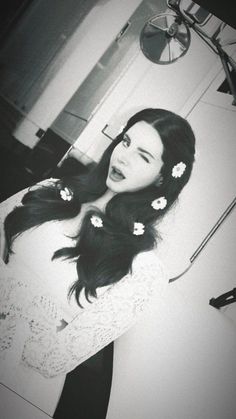 black and white photograph of a woman with long hair wearing flowers in her hair, looking at the camera