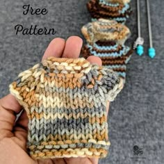 a hand is holding two knitted mitts with the words free pattern on it