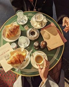 a person sitting at a table with coffee and croissants