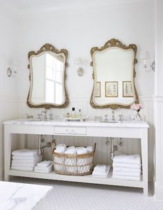 a white bathroom with two mirrors above it