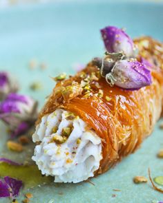 a piece of sushi on a plate with flowers and other food items around it