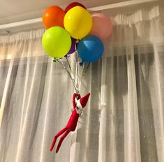 a cat in the hat balloon is hanging from a curtain rod with balloons attached to it