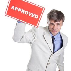 a man in a suit holding up a sign that says approval over his shoulder and the words approved on it