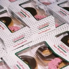 several boxes of doughnuts with pink frosting and sprinkles