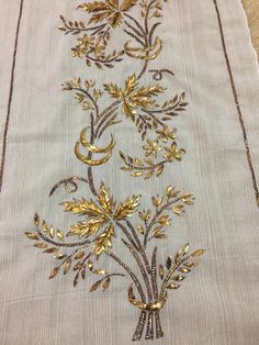 an embroidered cloth with gold flowers and leaves