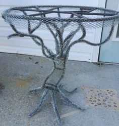 a wire tree table sitting on top of a cement floor next to a garage door