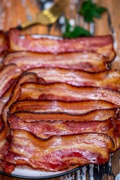 slices of bacon on a white plate sitting on a wooden table