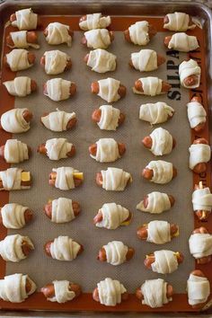 pigs in a blanket on a baking sheet covered with white icing and hotdog buns