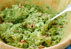 a wooden bowl filled with guacamole and a spoon