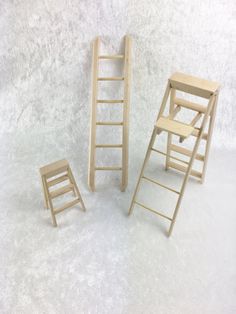 three miniature wooden ladders sitting next to each other on a white surface with snow