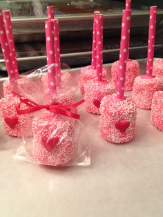 candy apples wrapped in pink and white polka dot paper with hearts on them are ready to be eaten